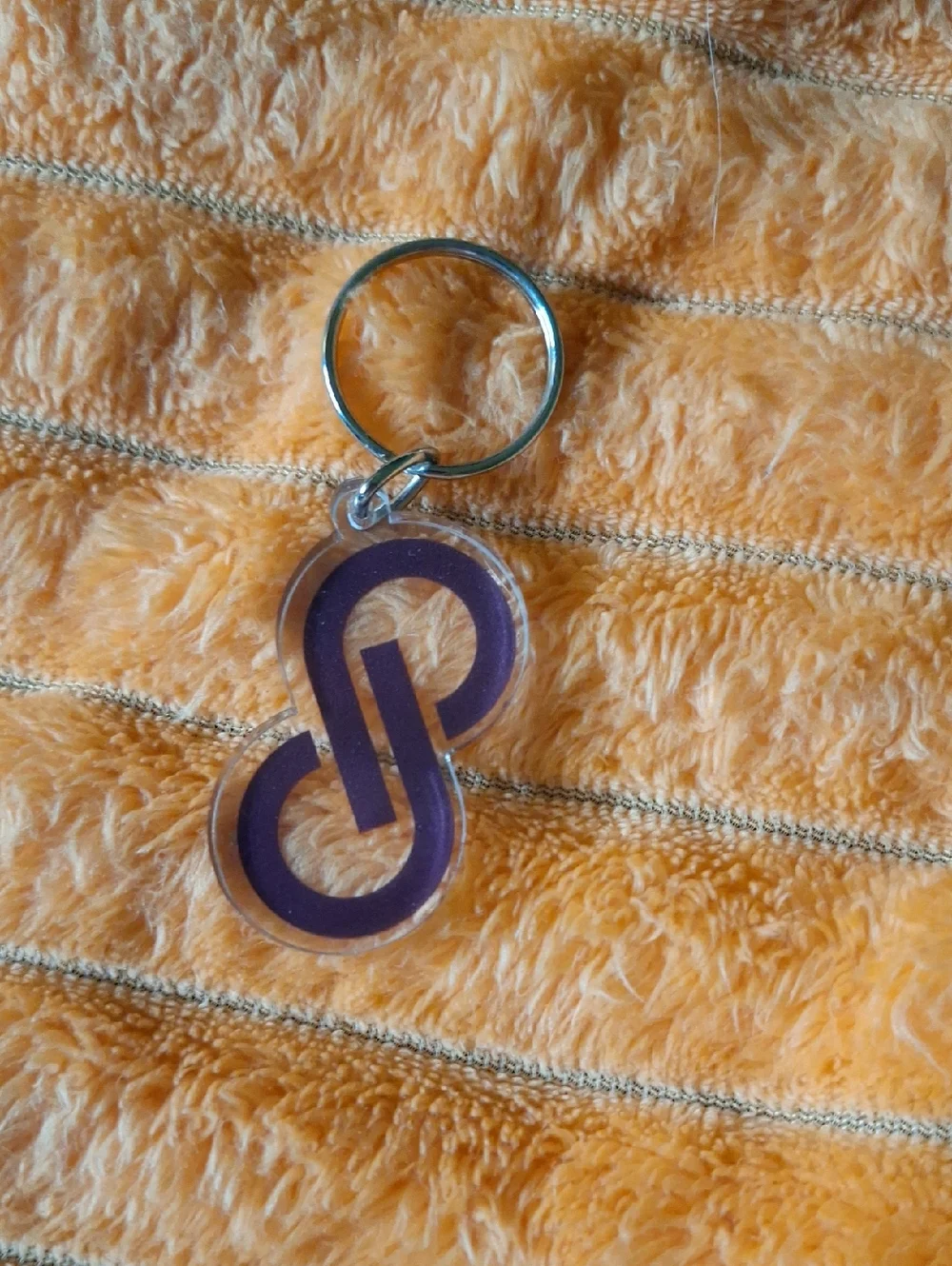 Clear acrylic keychain featuring a bold purple interlocking Poshmark logo.